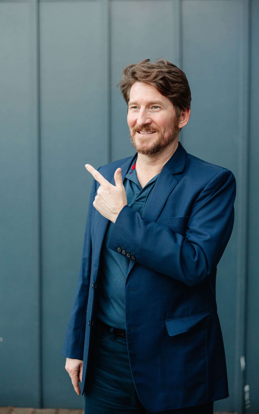 Dylan Cornelius, career coach, in a navy blazer, pointing toward the Modern Career Playbook